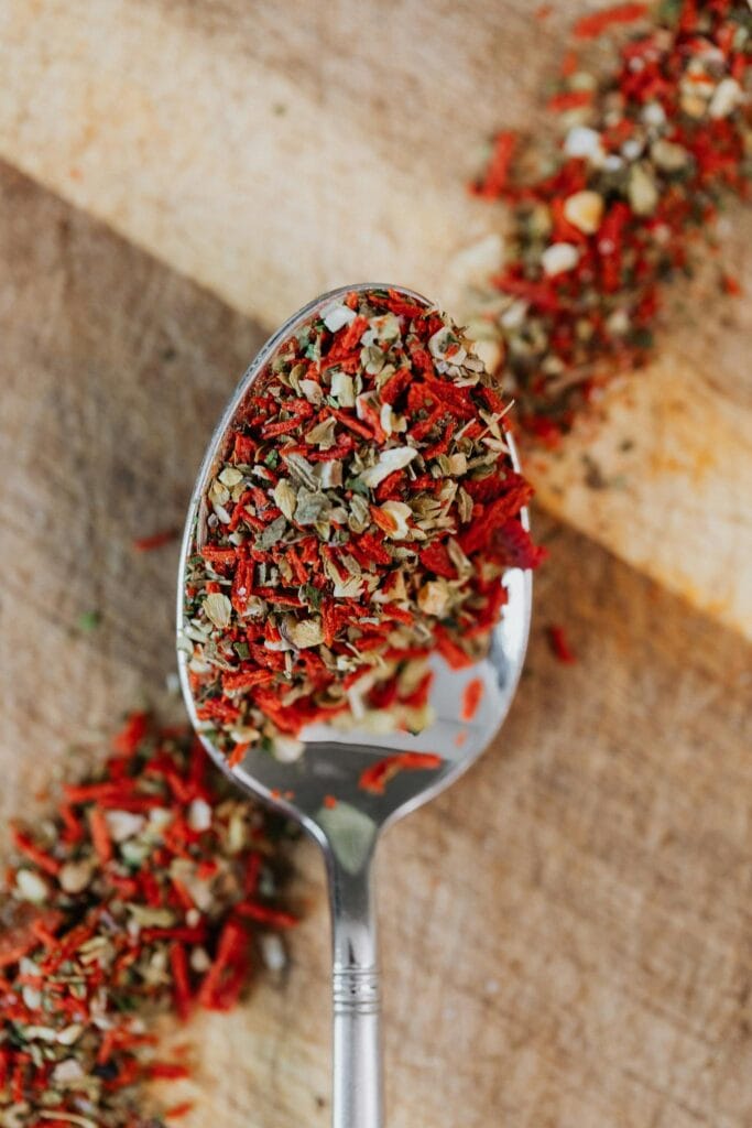 Close-up of mixed herbs and spices on a spoon over wooden surface.